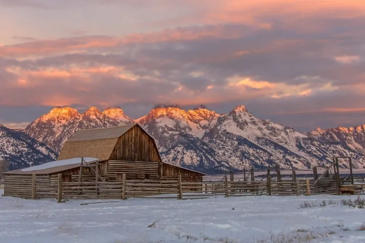 a house covered in snow with a mountain in the background