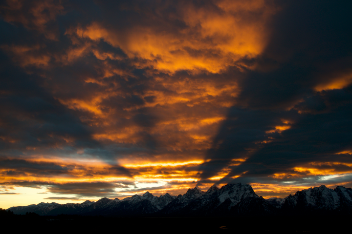 Sun setting behind the Tetons with clouds glowing orange